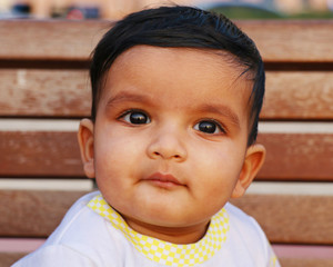 one year old cute baby boy looking something with a  little smile