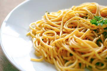 Plate of spaghetti pasta with vegetables on white plate, served on green napkin, close-up of Italian meal. 
