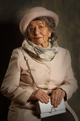 Fototapeta na wymiar Portrait of an old woman in a hat, scarf and handbag