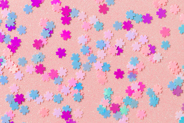 Small sakura flowers on a sparkling paper, glitter pink flowers, shimmering spring background
