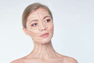 portrait of a young beautiful woman with drawn massage lines on her face. skin lifting concept....