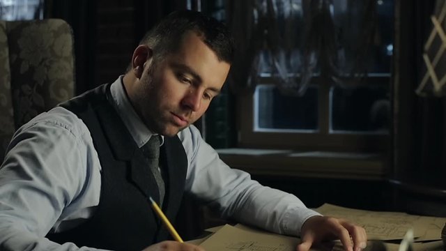 Man sitting at an old desk and writes a pen