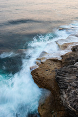 Water flowing into rocks in the coastline.