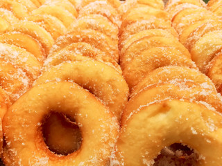 Closeup and crop lots of doughnut with sugar on shelf in the bakery shop background and wallpaper. Doughnut is the one causes disease of Coronary Artery Disease and Obesity.