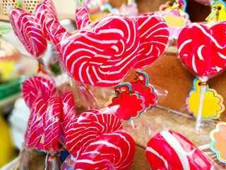 Closeup and crops colorful sweet lollypops with labels for sale on wooden shelf background.