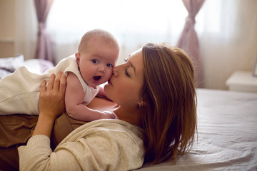 young mother with red hair is lying on the bed with her daughter