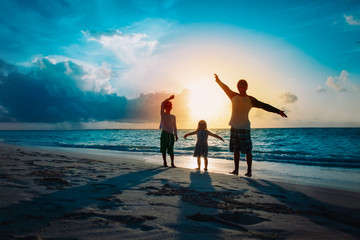 Fototapeta premium father with son and daughter silhouettes play at sunset beach