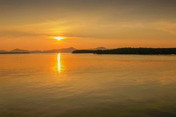 Sea view evening of sundown with yellow sun light and cloudy sky background, sunset at Kuraburi Pier, Phang Nga, southern of Thailand.