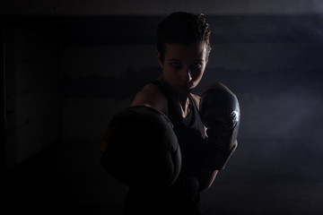 Silhouette portrait of young woman punching with boxing gloves