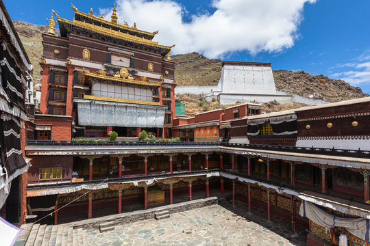 Front view of Tashi Lhunpo (Tashilhunpo) Monastery  in courtyard on summer sunny day with blue sky and cloud, Thanka wall in background, Shigatse, Tibet, China