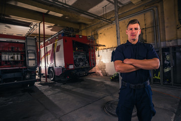Fototapeta na wymiar Portrait of confident young fireman standing inside the fire departmant