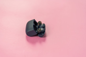 Wireless headphones on pink table with background