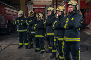 Group of firefighters standing confident with arms crossed. Firemen ready for emergency service.