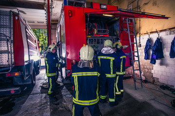 Group of firefighters preparing and inspecting pressure and water in the fire truck inside the fire station