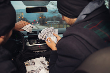 Two happy bank robbers celebrating their successful hit while sitting in the car they used for the...