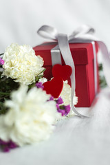 gift box, flowers and hearts.Concept of love, birthday, Happy mother's Day and Valentine's day on a white fabric background. Gift card. Selective focus.