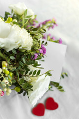 Postcard with a flowers, heart and an empty tag for text. Romantic greeting and surprise. Concept of love, Happy mother's Day and Valentine's Day on white background. Selective focus. copy space