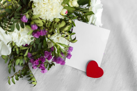 Postcard with a flowers, heart and an empty tag for text. Romantic greeting and surprise. Concept of love, Happy mother's Day and Valentine's Day on white background. Selective focus. copy space