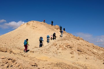 Unrecognized group of hikers on scenic trail in Negev desert mountains, Israel