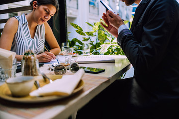 Office woman drinking coffee while writing on notebook in a restaurant