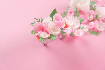 Hello, spring. Shopping cart with white and pink paper flowers and green leaves