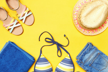Summer beach accessories on a yellow background. Hat, shorts, bikini, towel and sandals. Top view copy space flat lay