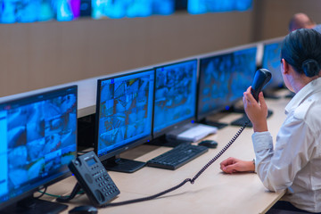 Security data center operator looking at the monitor while talking on a phone. Close up photo.