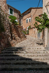 Fototapeta na wymiar Alte enge Gasse mit Steinhäusern und Treppen in Fornalutx, Mallorca