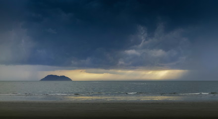 view seaside of small island in the sea with raining and dark clouds moving in the sky background, sunset with raining at Laem Son beach, Laem Son National Park, Ranong, southern of Thailand.