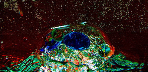 large glass transparent ball inside the water with air bubbles and colorful pieces of artificial ice
