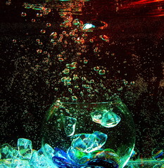 large glass transparent ball inside the water with air bubbles and colorful pieces of artificial ice