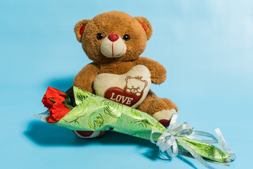 Teddy bear holding bouquet of red roses valentines day
