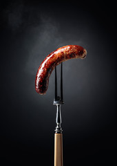 Fototapeta Grilled Bavarian sausage on a fork. obraz
