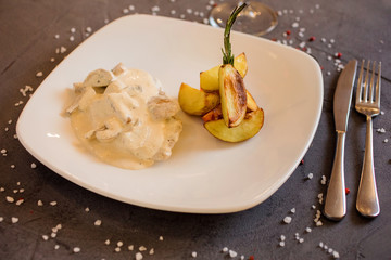 Close up view of delicious pork and mushrooms in the creamy sauce and potatoes on the white plate. Restaurant menu concept.