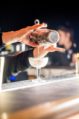 bartender is preparing a cocktail. Bartender pours a cocktail