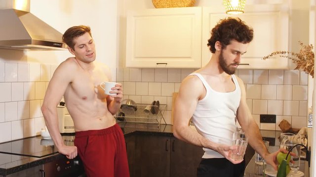 Morning, breakfast. Two young sexy guys in the kitchen. Love and relationships.