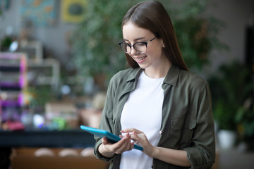 Young girl in glasses with a tablet in her hands.