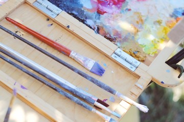 oil paint, palette, and tools of an artist. Colorful workplace of the artist with brushes and oil paints in the plein air.
