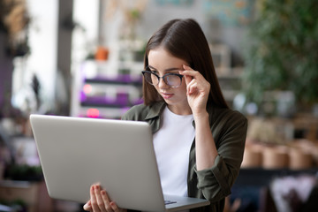 Girl in surprise looking at laptop screen holding it in hand.