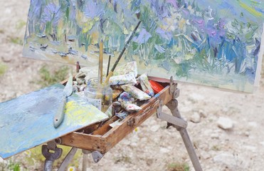 Colorful workplace of the artist with brushes and oil paints in the plein air.