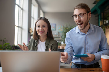 Young girl and man looking at a laptop, delighted.