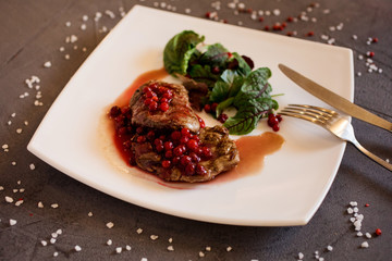 Delicious beef steakcovered with lingonberries and beet tops on the white plate. Restourant menu concept.
