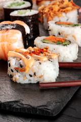 Sushi set close-up with chopsticks on a black background