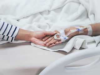 Obraz premium Hands of the old woman and a young woman while lying in bed in a hospital.