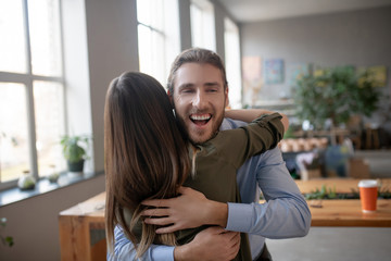 Smiling bearded man hugging his female friend