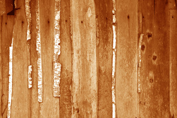 Wall made of uncutted weathered wood boards in orange tone.