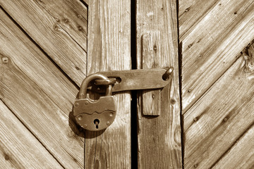 Grungy wooden door with lock in brown tone.