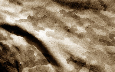 Part of military camouflage uniform close-up with blur effect in brown tone.