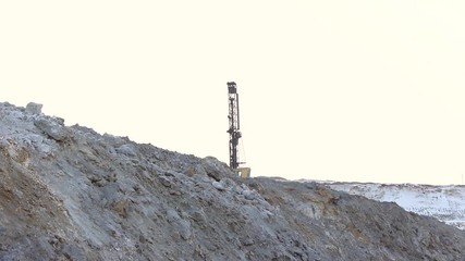 The drilling rig does its job in an open pit. Drill is drilling. - Powered by Adobe