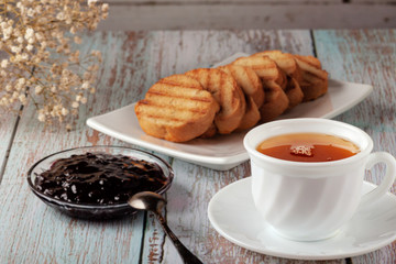 Freshly made tea in a teapot with cookies and jam on the table